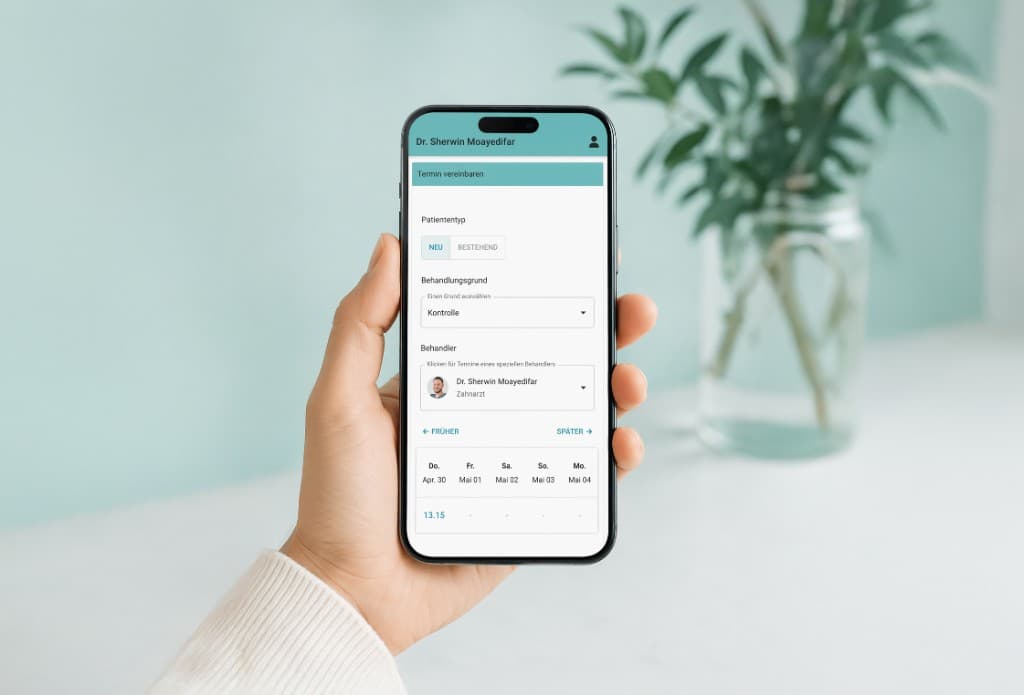 Smartphone mit Online-Terminbuchung für Zahnwohl Penzing: Formular mit Patiententyp, Behandlungsgrund und freien Zeitslots, Hand mit hellem Pullover